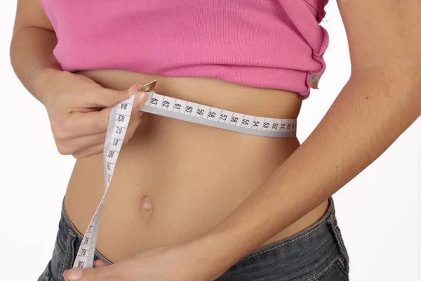 Een jonge vrouw meten haar taille geïsoleerd op witte achtergrond — Stockfoto