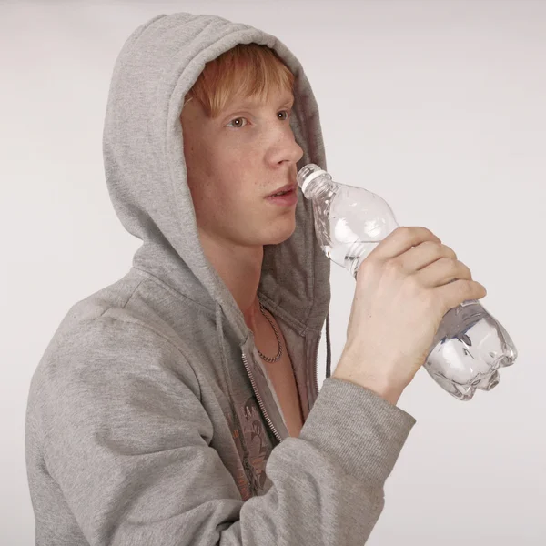 Młody człowiek pije wody na szarym — Zdjęcie stockowe