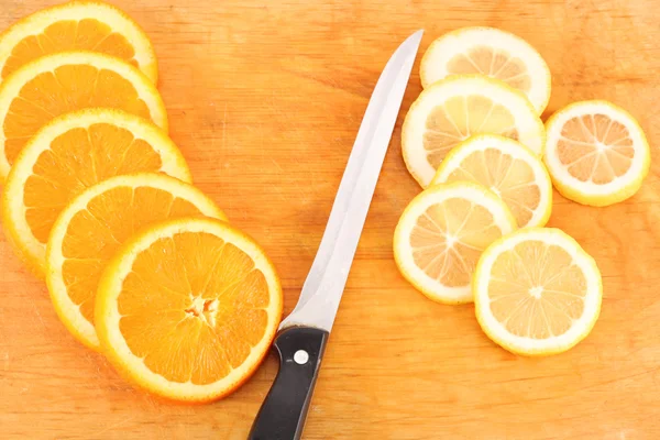 Sliced orange, lemon with a kitchen knife on a chopping board — Stock Photo, Image