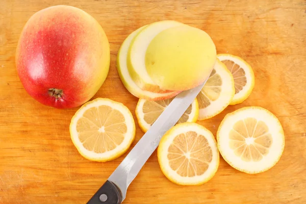 stock image Sliced ​​lemon, apple and a knife on the board