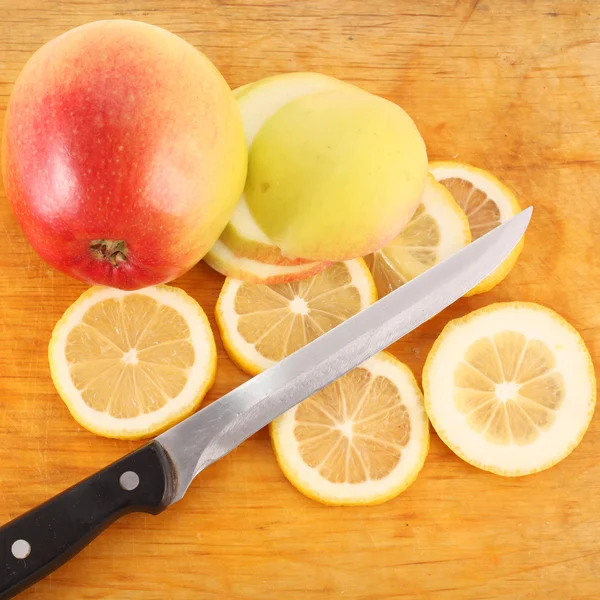 Sliced ​​lemon, apple and a knife on the board — Stock Photo, Image