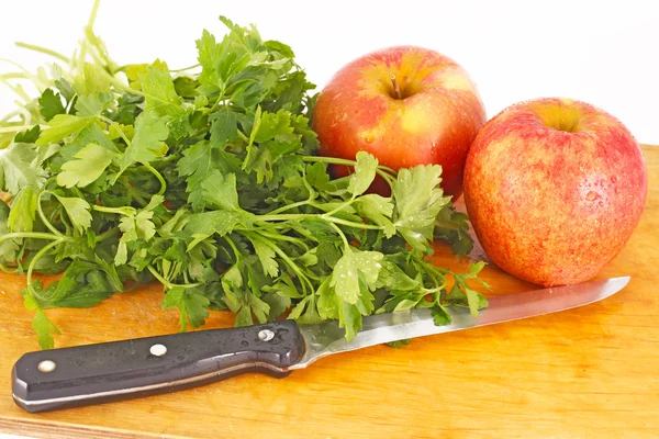 Red apples, parsley and a knife on a wooden chopping board — Stock Photo, Image