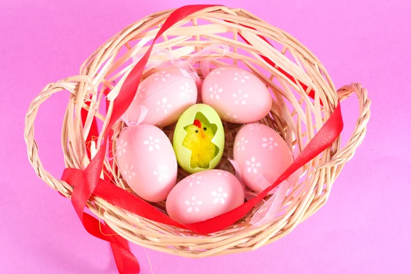 Osterkorb gefüllt mit Eiern und Hühnern auf rosa Hintergrund — Stockfoto