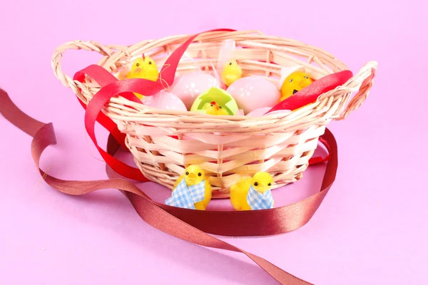Wielkanocny koszyk wypełniony z jaj i z kurczakiem na różowym tle — Zdjęcie stockowe