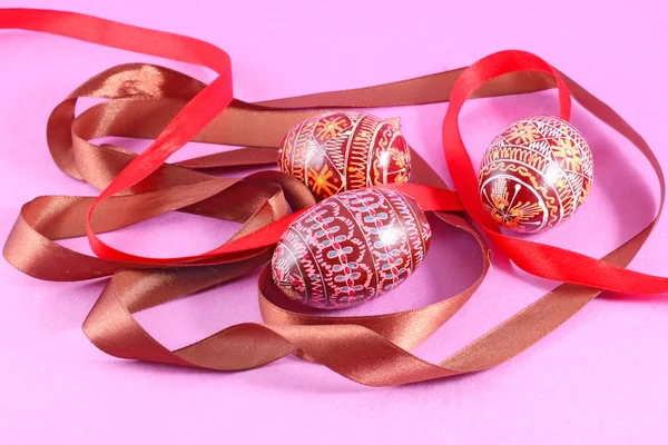 stock image Colorful easter eggs , with a ribbon , on a pink background