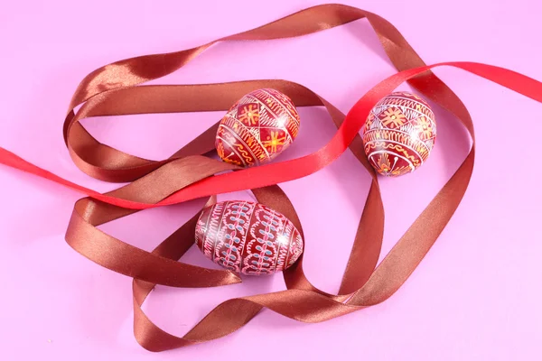 Stock image Painted Easter eggs Pysanka with ribbon on pink background