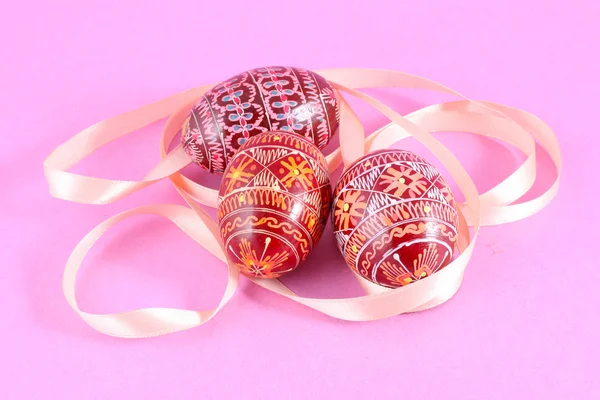 Painted Easter eggs Pysanka with ribbon on pink background — Stock Photo, Image