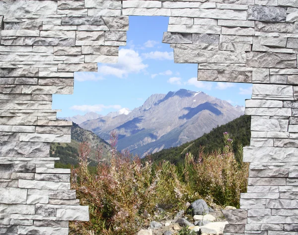 Uma paisagem de montanha em uma janela atrás de uma parede de pedra — Fotografia de Stock
