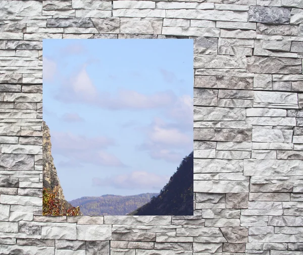 Een berglandschap in een venster achter een stenen muur — Stockfoto