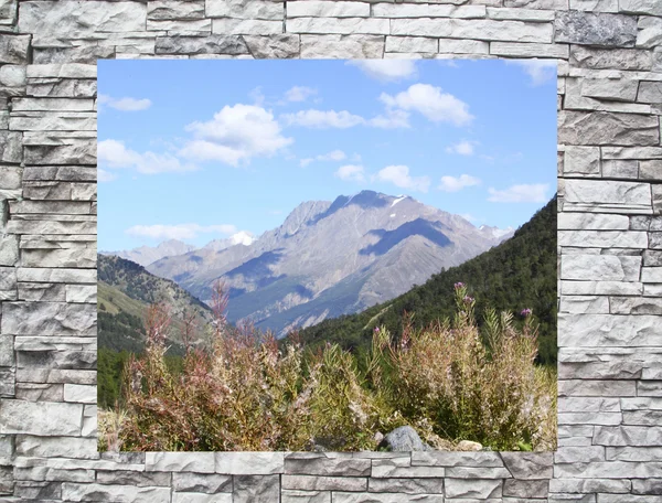 Ett bergslandskap i ett fönster bakom en stenmur — Stockfoto