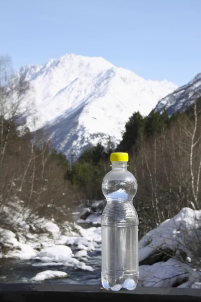 Láhev čisté vody proti majestátní sněhu nahoře Stock Snímky
