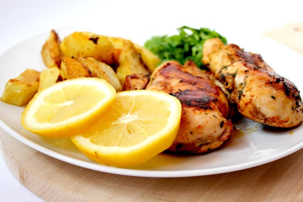 Roast chicken with baked potatoes, lemons and green — Stock Photo, Image