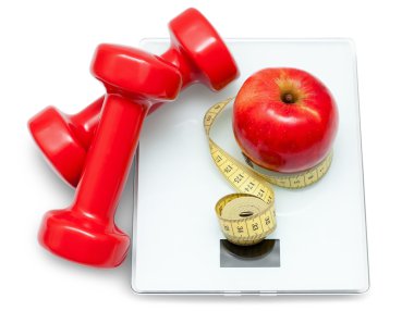 Scales, dumbbells, red apple and measuring tape