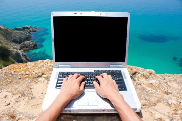 Händer med laptop på stranden — Stockfoto