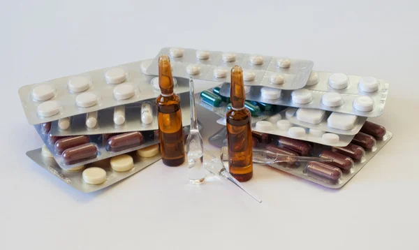 Разноцветные таблетки и ампулы на столе — стоковое фото