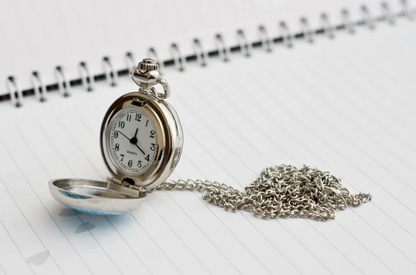 Pocket watch placed on the booknote. Silver. — Stock Photo, Image