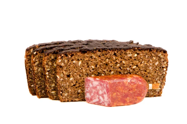 Corte trozos de salchichas ahumadas y granos de pan oscuro —  Fotos de Stock