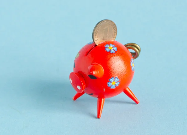 Rotes Sparschwein mit Pfennig auf blauem Hintergrund — Stockfoto