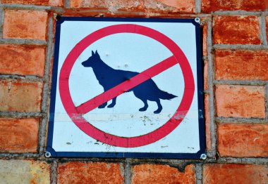 Sign prohibiting walk out dogs in park on red brick house wall clipart