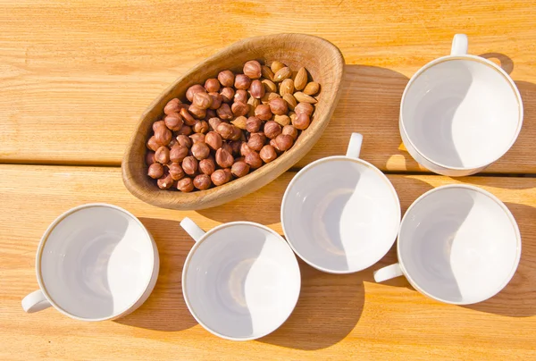 Paquete de avellanas en tazas de plato de madera colocadas en la mesa —  Fotos de Stock