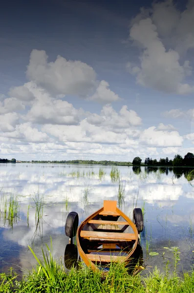Csónak kikötve gumi abroncsok felhő tükrözi a víz — Stock Fotó