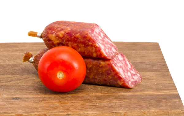 Corte pedaços de salsicha defumada e placa de corte de tomate — Fotografia de Stock