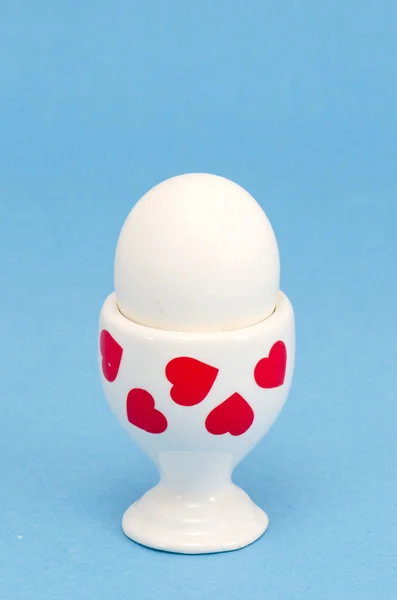 Huevo blanco en taza especial comiendo sobre fondo azul — Foto de Stock