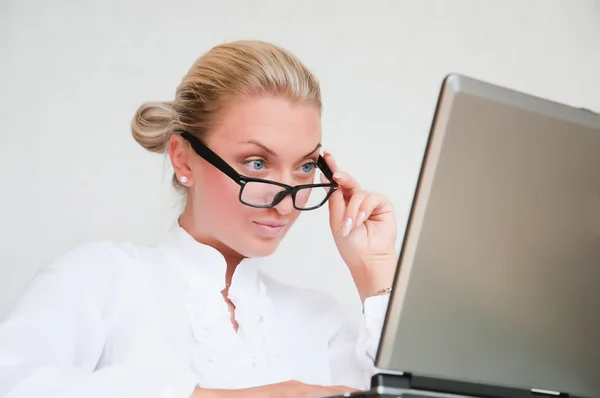 Atractiva joven mujer de negocios utilizando el ordenador portátil en el escritorio — Foto de Stock