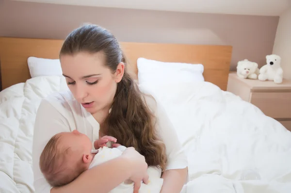 Portret van jonge gelukkig moeder met pasgeboren baby thuis — Stockfoto