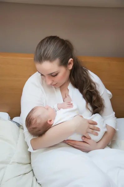 Portret van jonge gelukkig moeder met pasgeboren baby thuis — Stockfoto