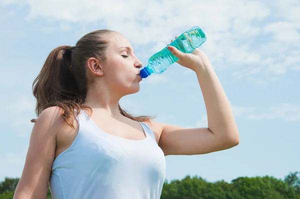 Beautiful girl drinking water against blue sky — Stock Photo, Image