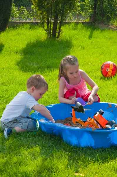 The boy and girl playing to a sandbox. — Stock Photo, Image