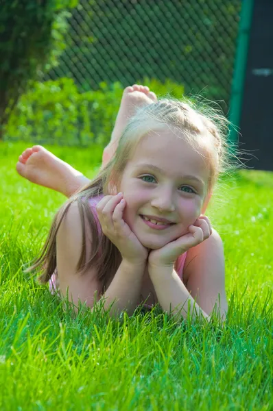 Счастливая маленькая девочка лежит в парке — стоковое фото