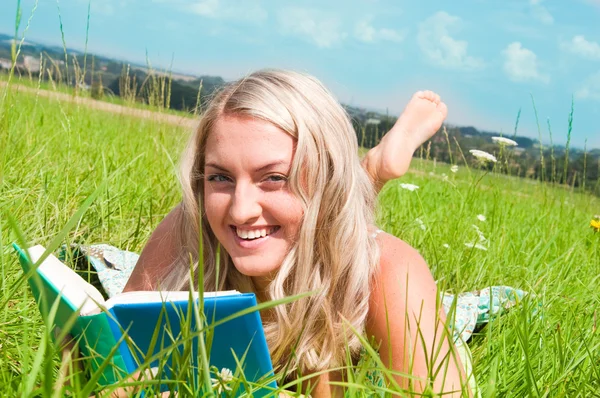 एक किताब के साथ घास पर सुंदर युवा लड़की — स्टॉक फ़ोटो, इमेज