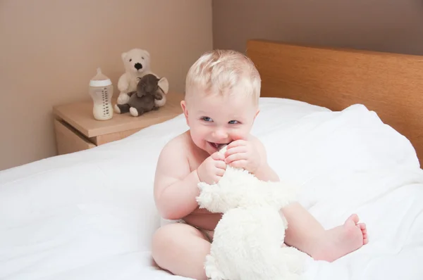 Baby gry gry na białe łóżko Miś — Zdjęcie stockowe