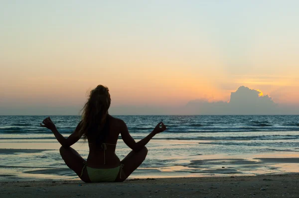 Meditating woman on the beach at sunset — Stock Photo, Image