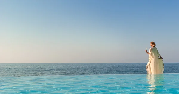 Mooie vrouw in Griekse stijl op infinity zwembad — Stockfoto