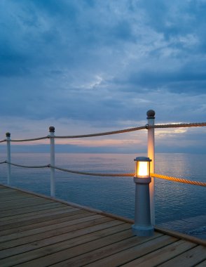 Wooden pier with lamp at sunset clipart