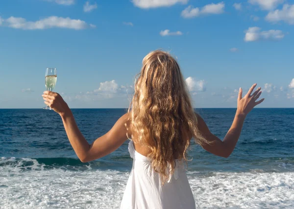 Vrouw in witte jurk in de buurt van zee ziet nu toe — Stockfoto