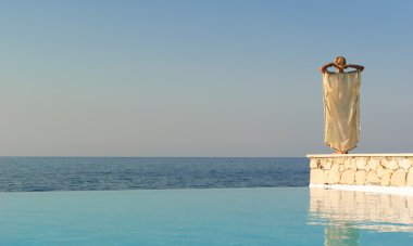 Rear view of greek style woman near infinity pool clipart