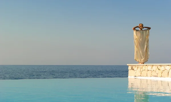インフィニティ プールのそばのギリシャ スタイルの女性の背面図 — ストック写真