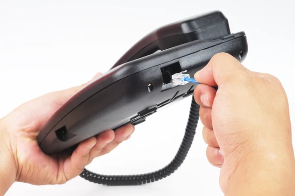 Eine Hand steckt ein Telefonkabel an die Steckdose — Stockfoto