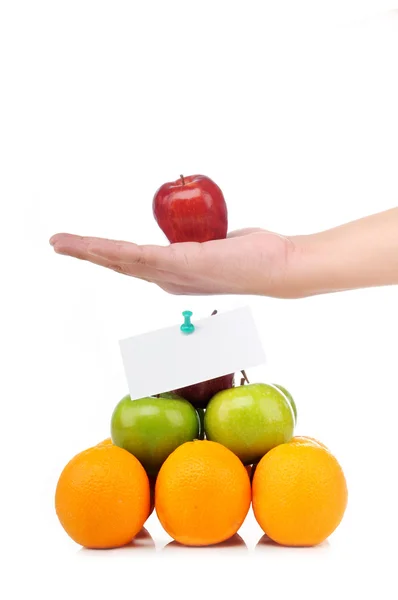 Pirâmide colorida de frutos com uma mão segura uma maçã — Fotografia de Stock