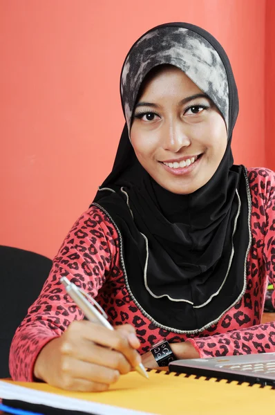 Vackra unga muslimska leende samtidigt skriva infront av anteckningsboken — Stockfoto