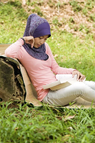Beautiful young muslim lady lean again the tree stump reading — Stock Photo, Image