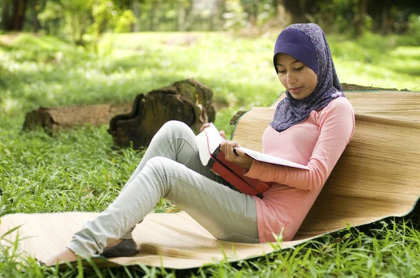 Güzel genç Müslüman Bayan yalın tekrar okuma ağaç kütüğü — Stok fotoğraf