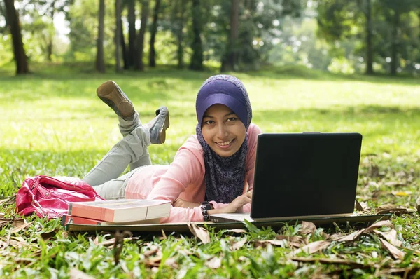 Linda jovem senhora muçulmana deitar-se no tapete na frente da nota — Fotografia de Stock