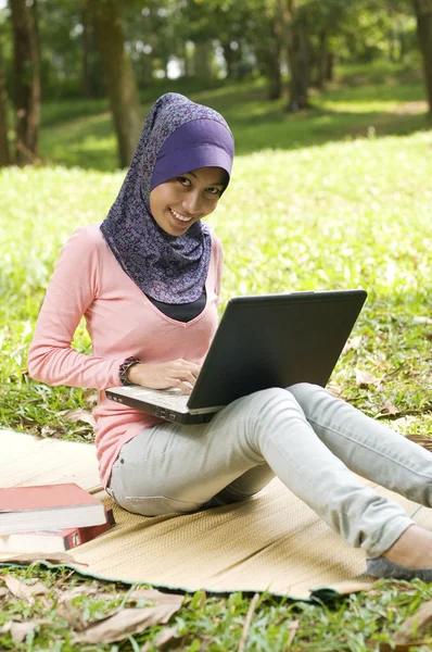 Linda jovem senhora muçulmana digitando no laptop enquanto se senta na ma — Fotografia de Stock