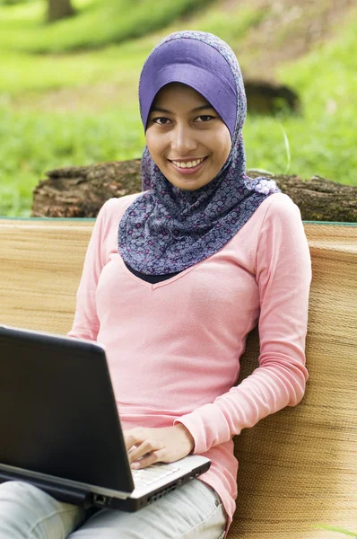 Schöne junge Muslimin lächelt vor dem Notizbuch — Stockfoto