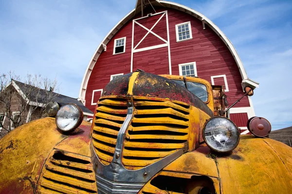 Modrá obloha, červená stodola, žlutý kamion. — Stock fotografie